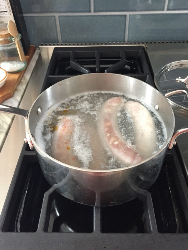 Parboiling the sausage in a saucepan.
