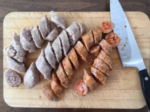 Sliced sausage on a cutting board with chef's knife