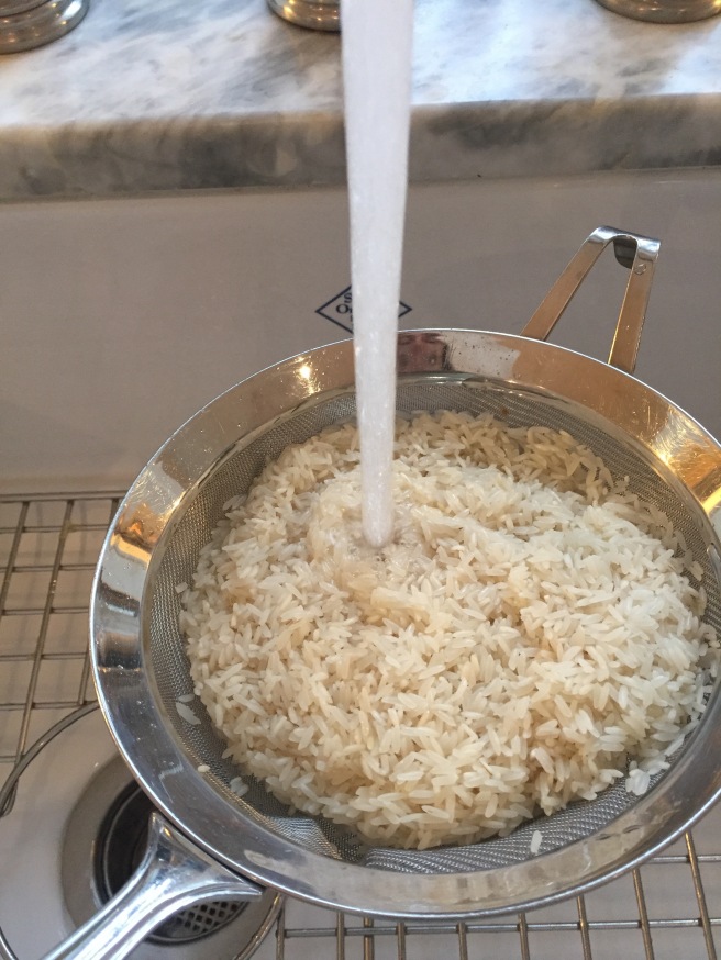 Rinsing and draining rice in mesh strainer